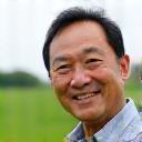 Photo of Akio Sato, a man who appears to be a farmer, smiling outdoors.